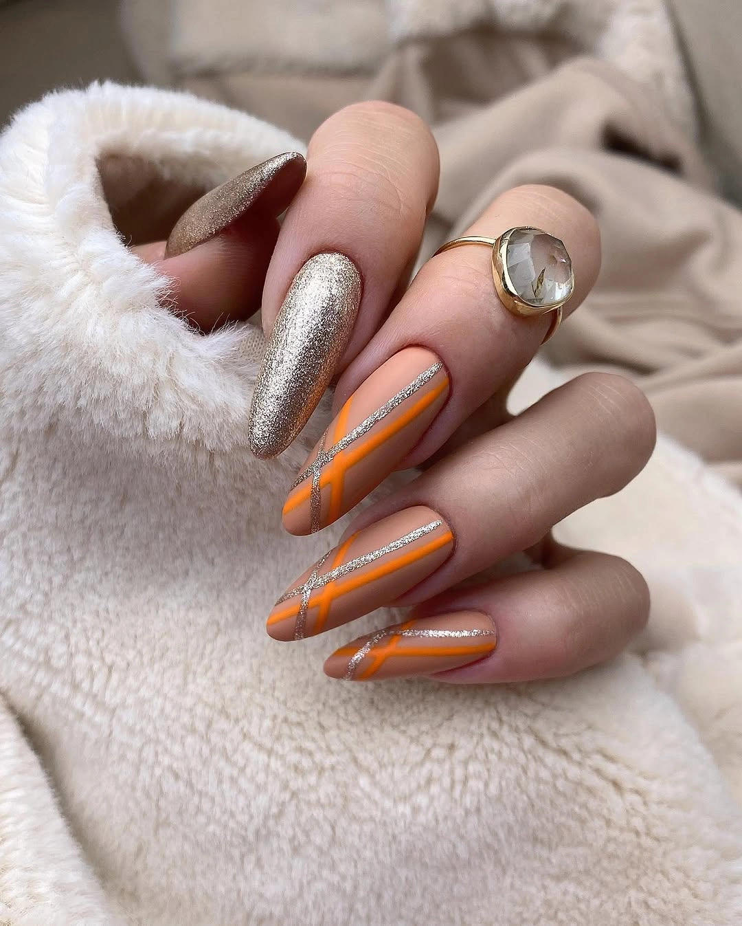 Long almond nails with orange bands and one silver accent