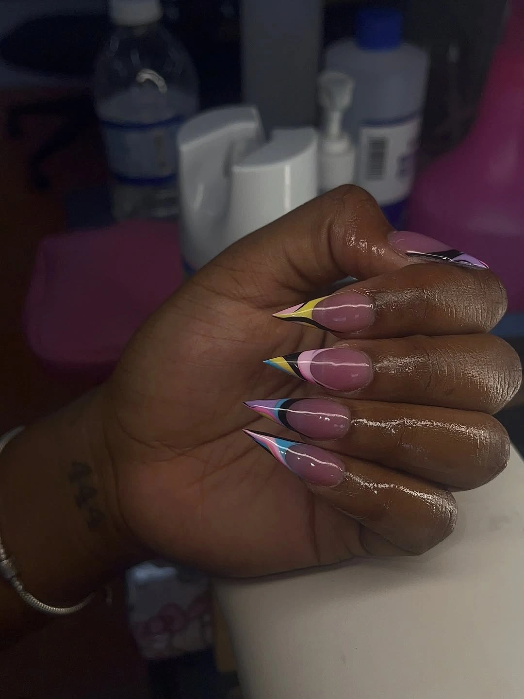 pink almond nails with layered green, blue, and white arcs