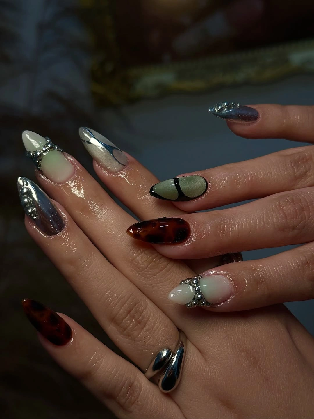 mixed almond nails with brown, green, blue-gray, and silver accents