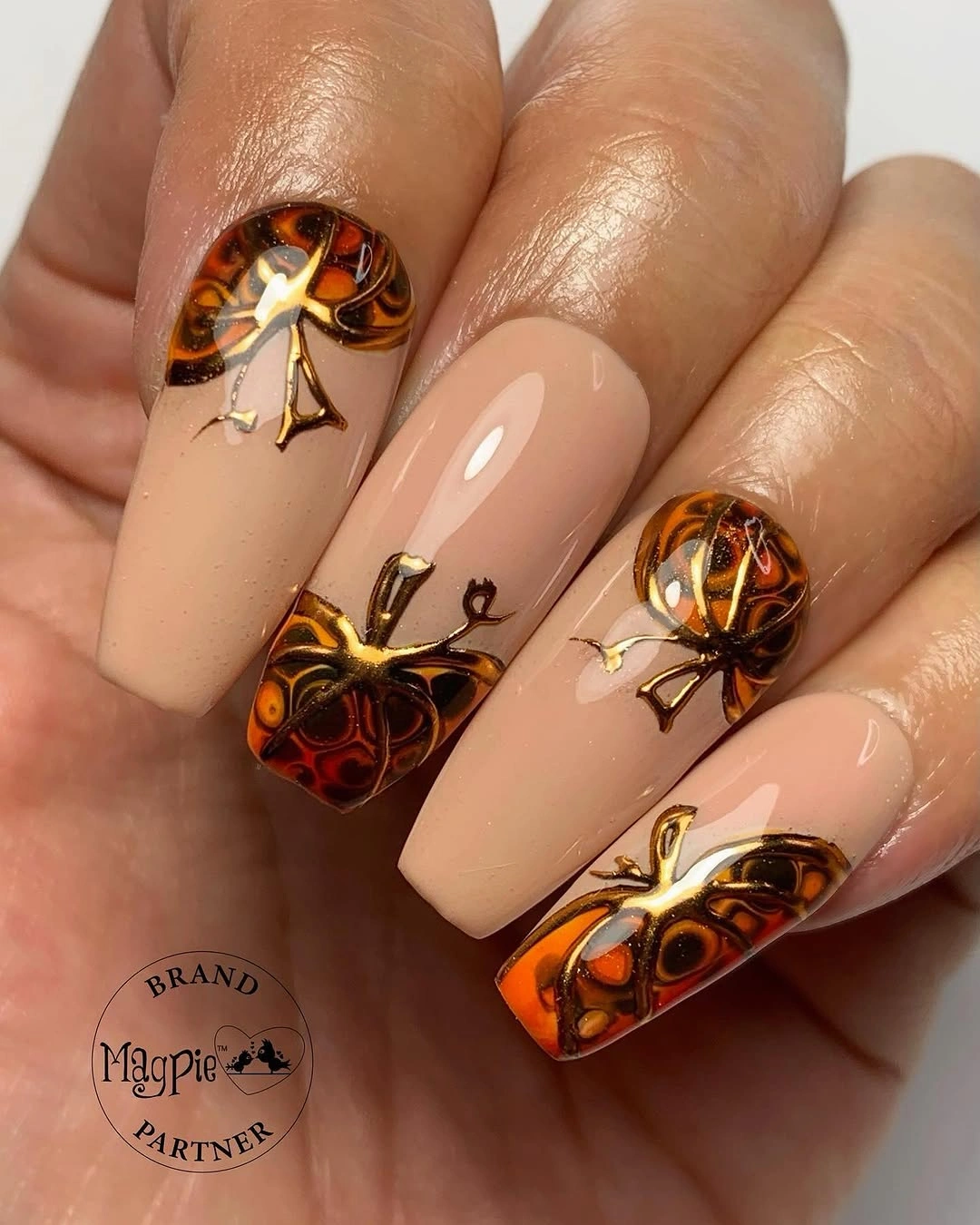 Nude square nails with amber wing-like gold accents
