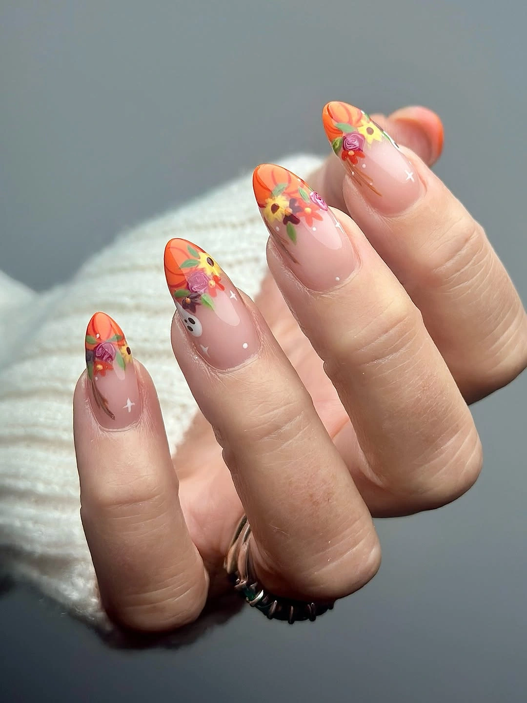 Medium almond nails with peach orange coral and green floral accents