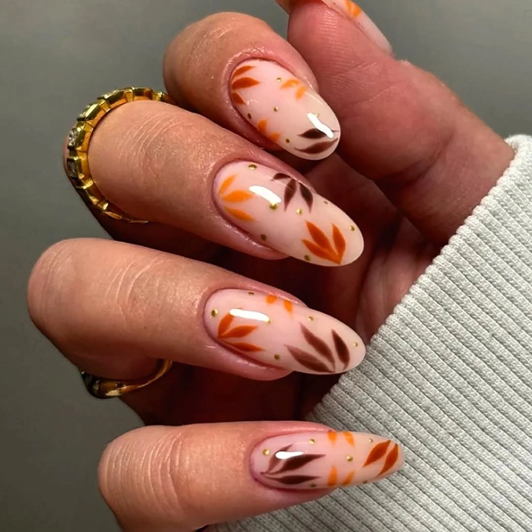 Milky pink almond nails with peach orange flame-like sweeps