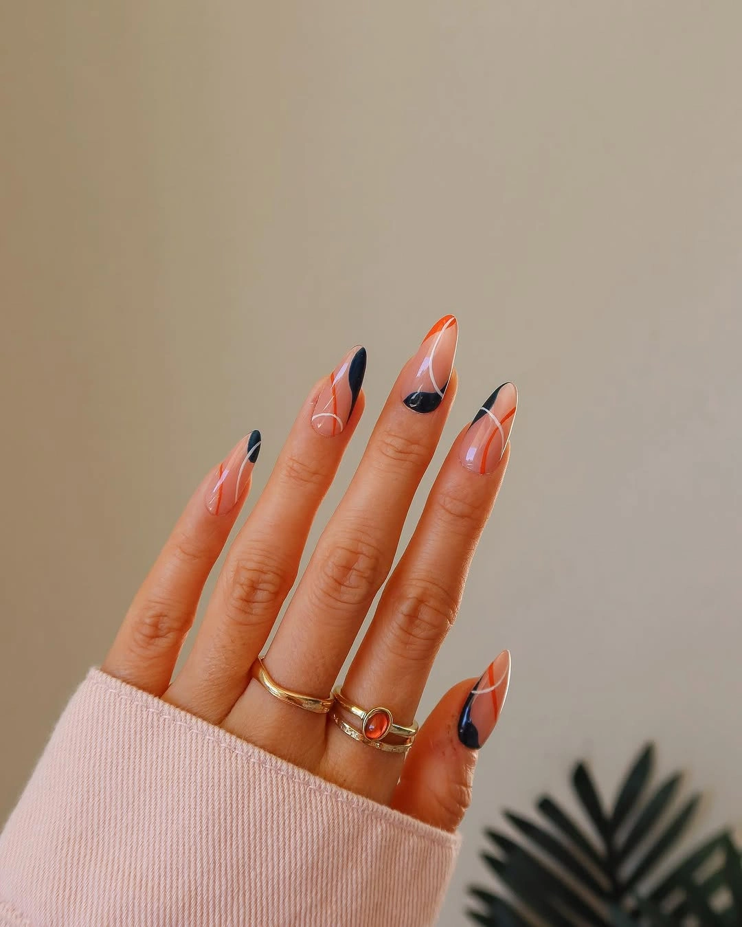 Long pointed nude nails with orange coral tips and dark outlines