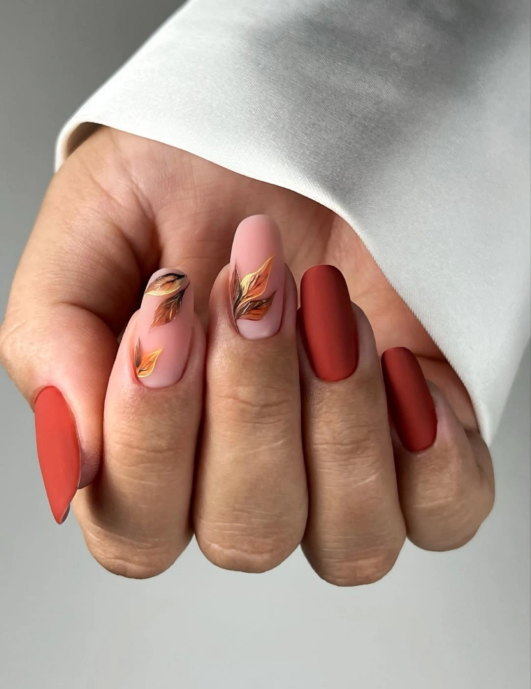 Medium oval nails with coral terracotta solids and nude linework
