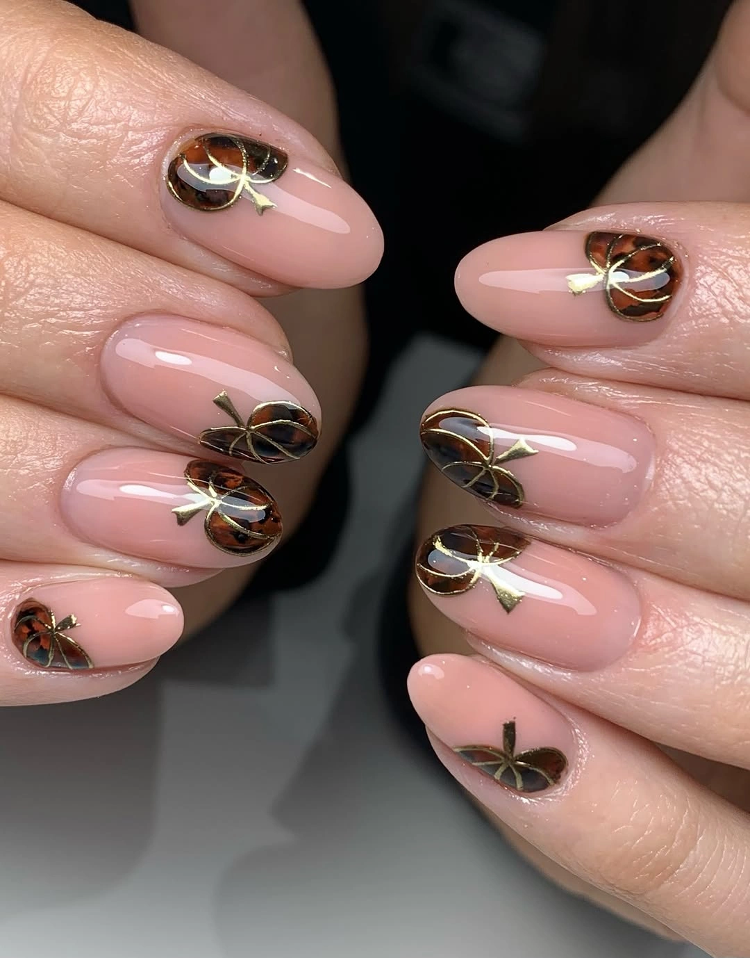 Translucent pink almond nails with gold loops and dark accents