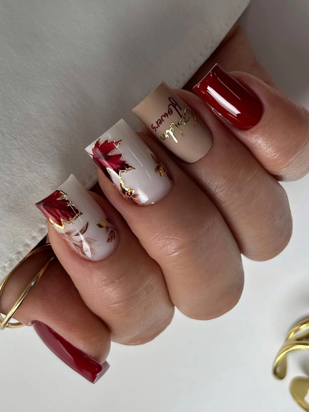 Medium square nails with burgundy tips white panels and warm accents