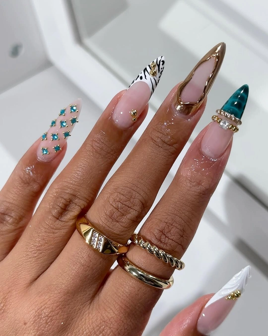 Stiletto nails with teal jewels gold and mixed accents