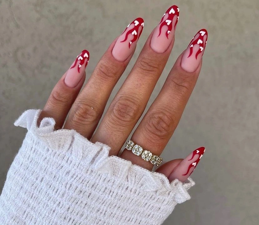 Long pale almond nails with red and white flowing wave accents