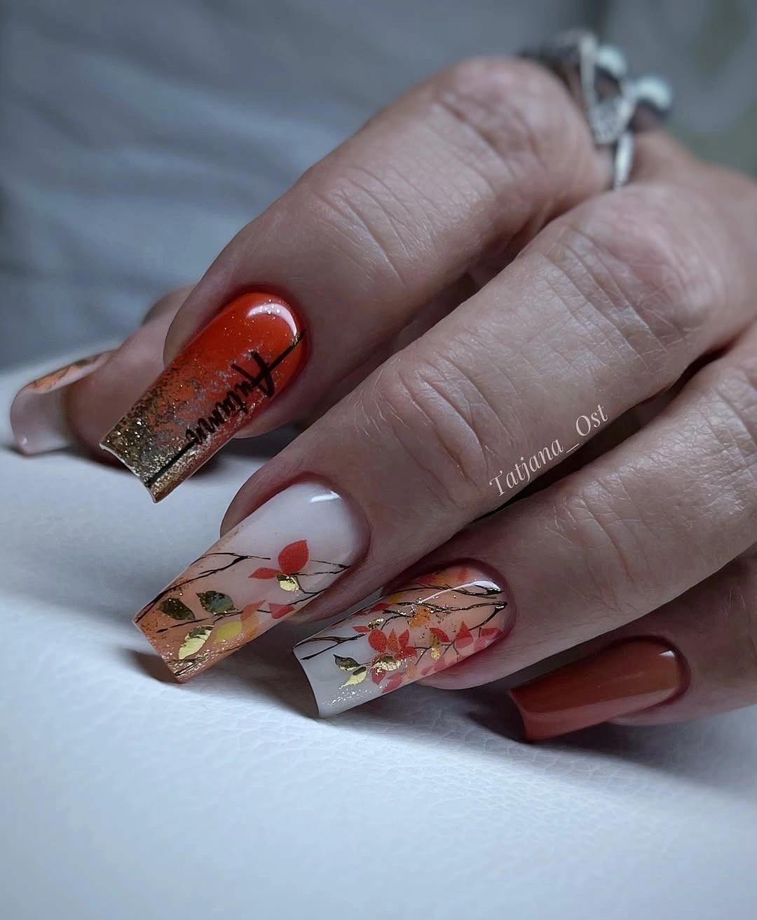 Long square orange nails with transparent floral panels and accents