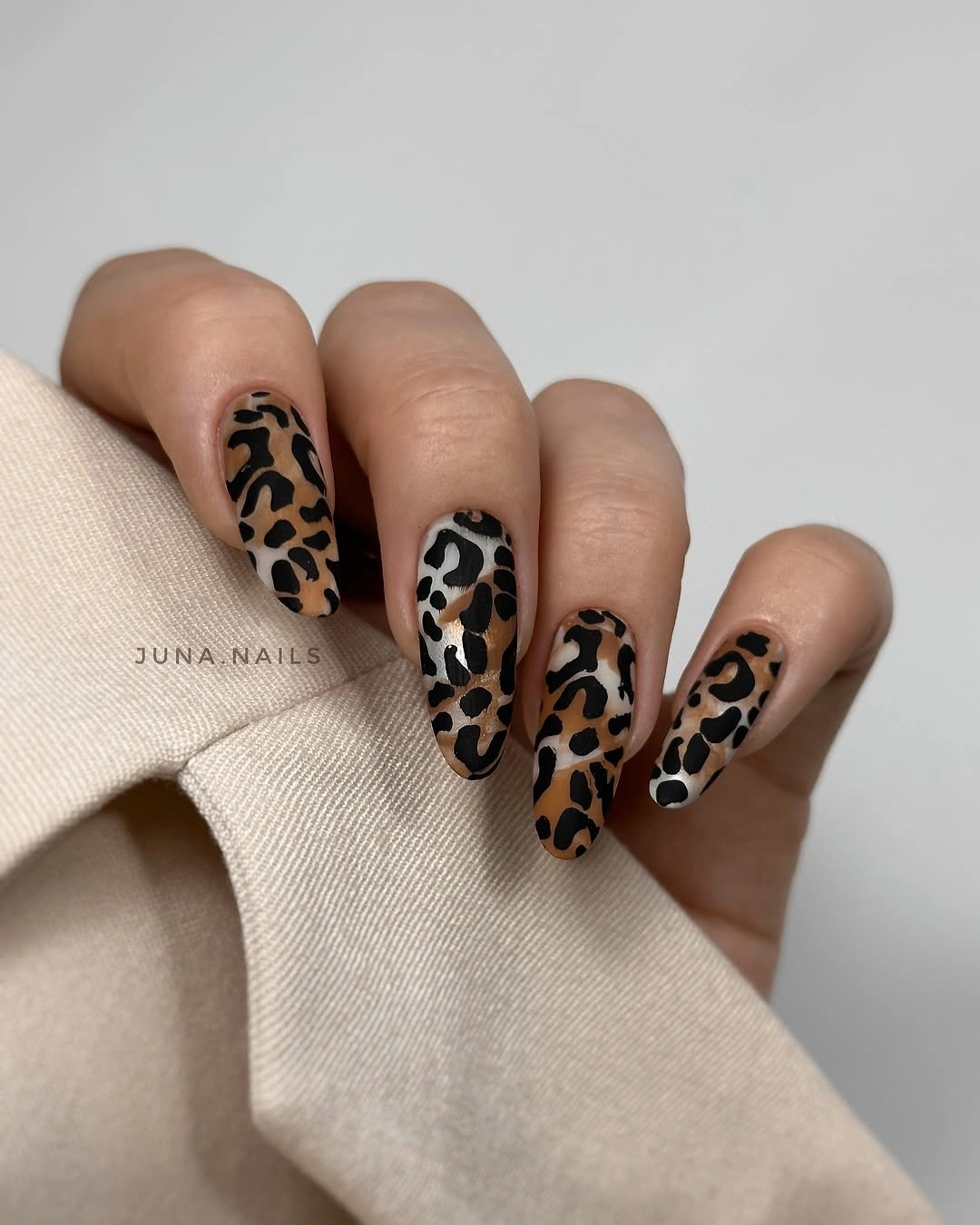 Medium beige almond nails with black and brown leopard spots