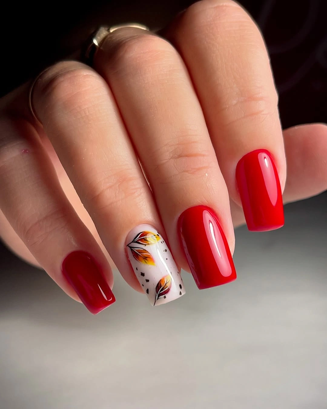 Glossy red square nails with one pale autumn floral accent