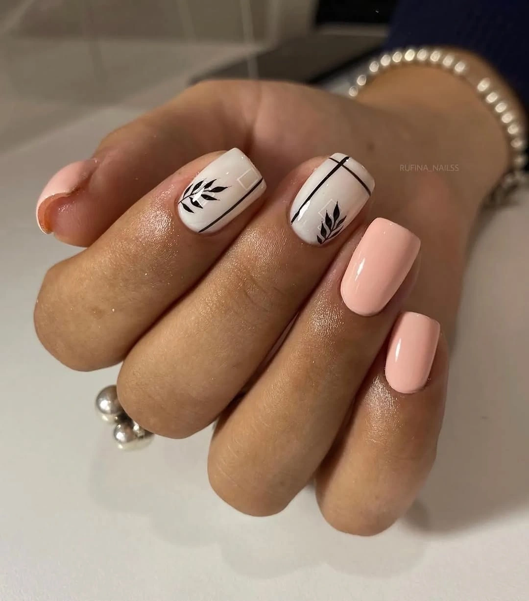 Short pale nails with delicate black botanical sprigs