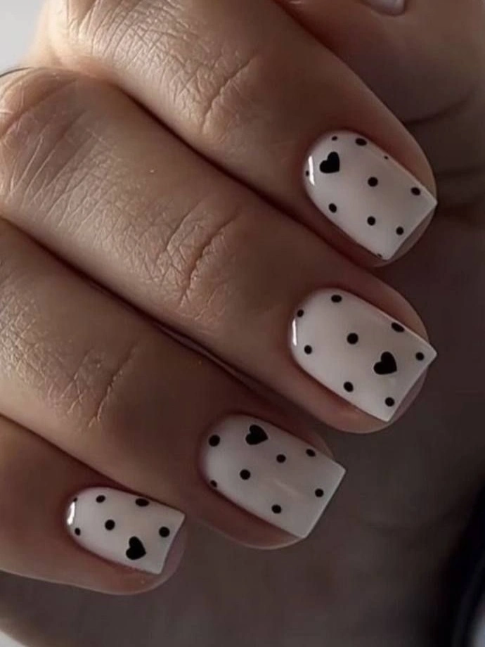 Short pale square nails with black dots and tiny hearts