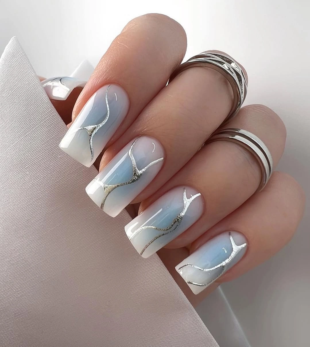 Milky blue square nails with cloudy panels and silver curves