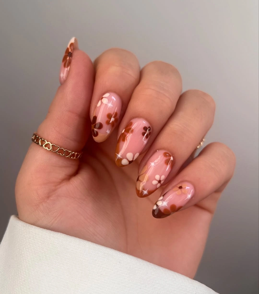 Sheer pink almond nails with brown flower accents