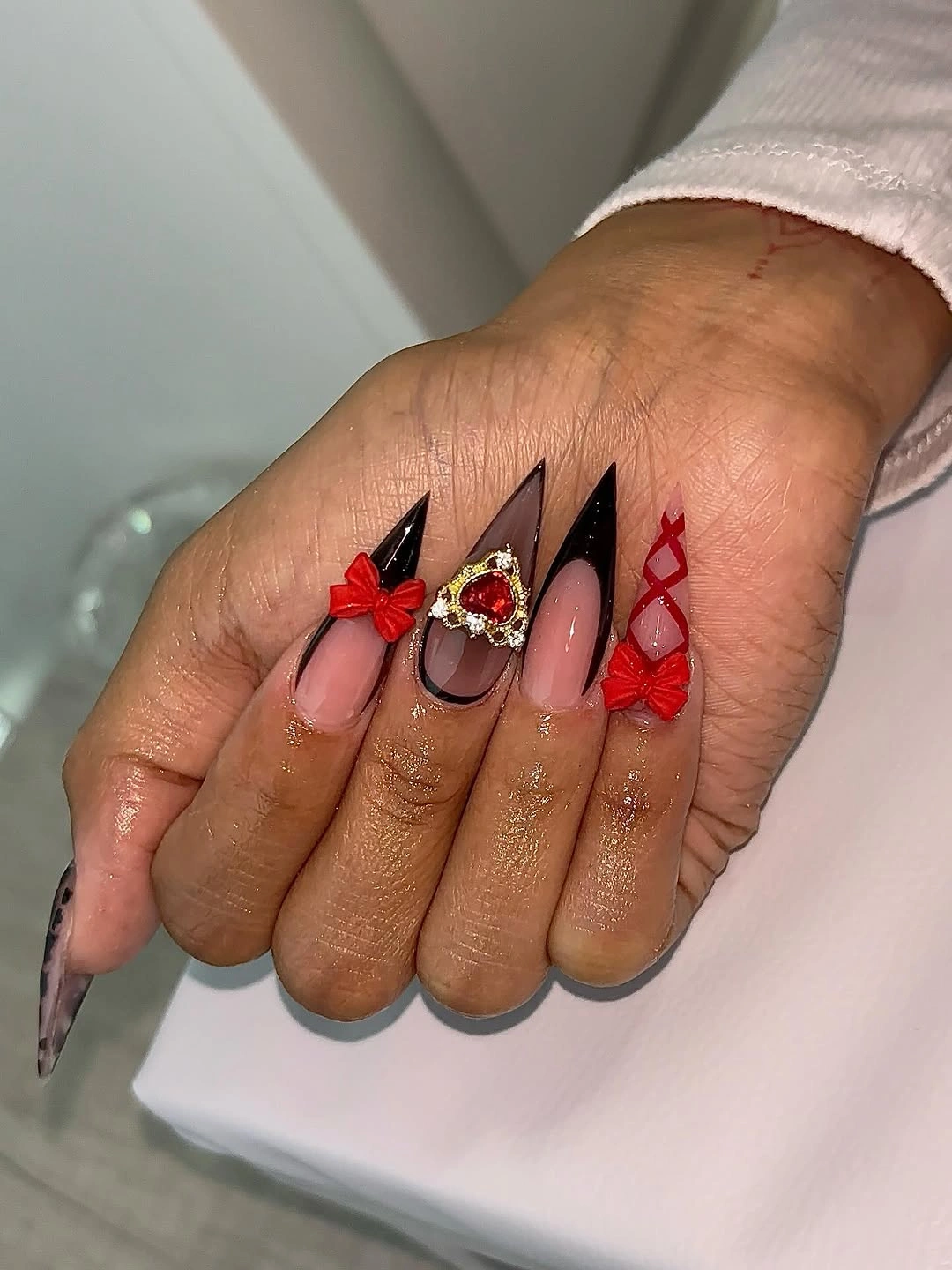 Pointed nude nails with red and black bow details