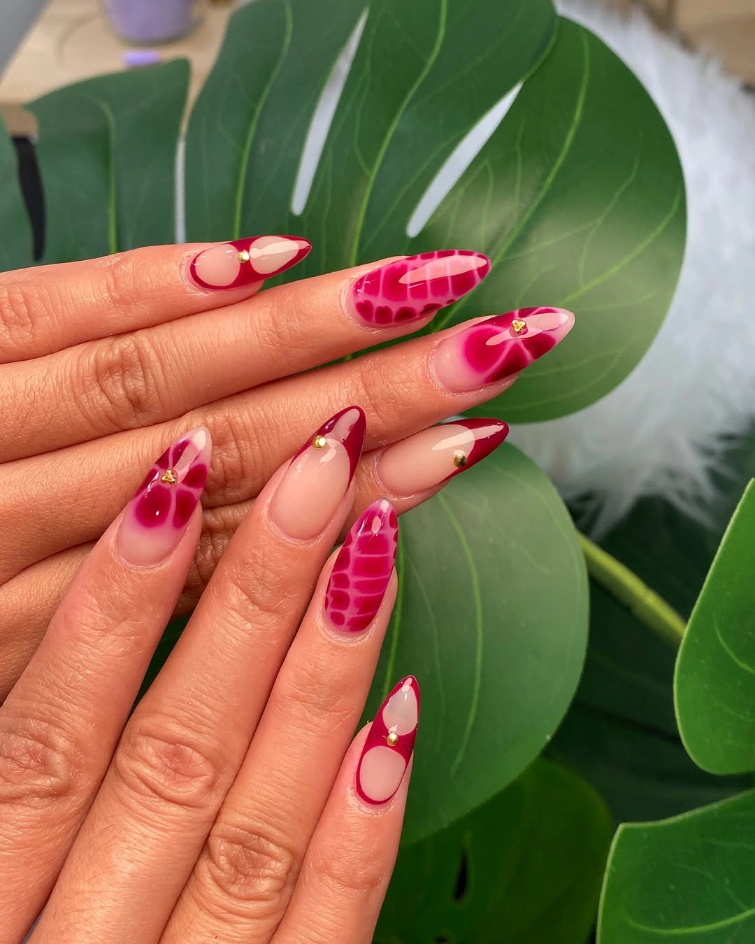Magenta almond nails with nude curves and gold studs