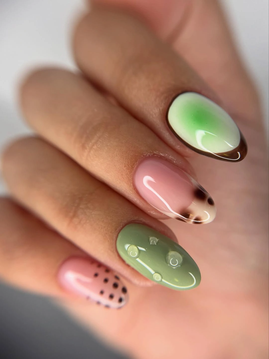 Sage green and blush nails with small black and white graphic accents