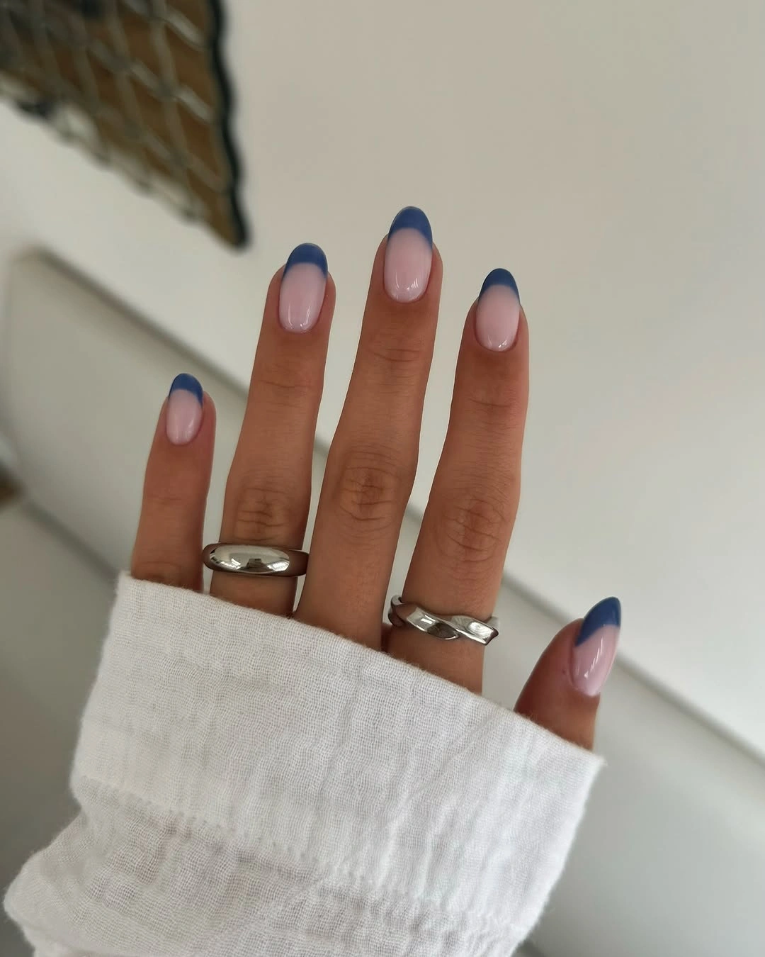 Medium oval nails with sheer pink bases and navy French tips