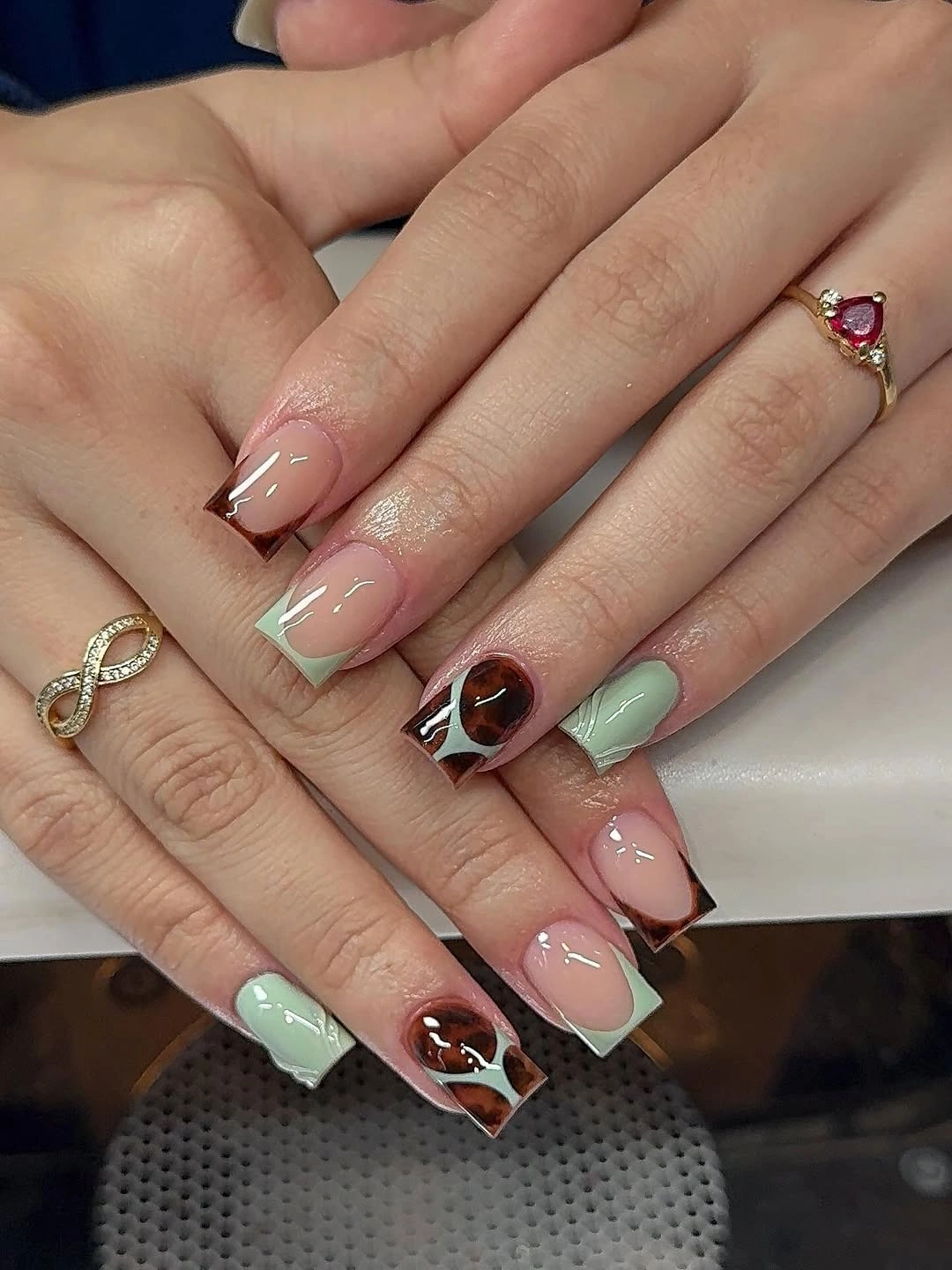 Pastel mint and pink French tips with one brown patterned accent
