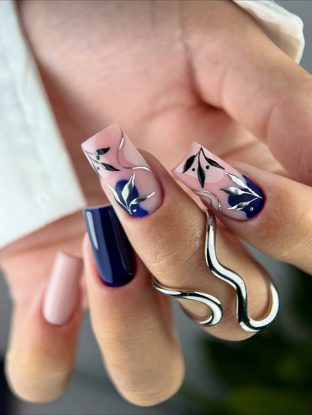 Pale almond nails with navy tips and abstract white black curves