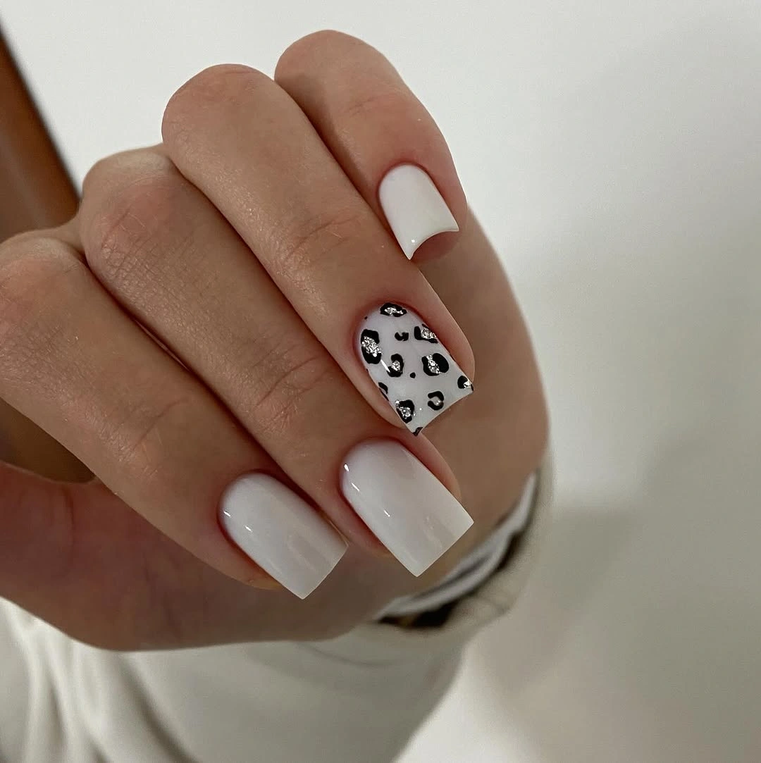 Short square white nails with one black spotted accent nail