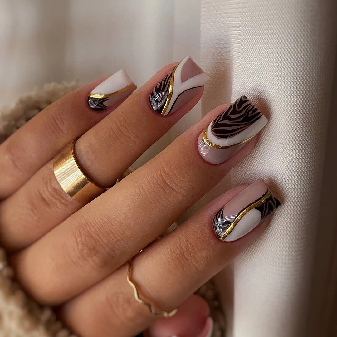 Medium pale nails with brown swirls and fine gold accents