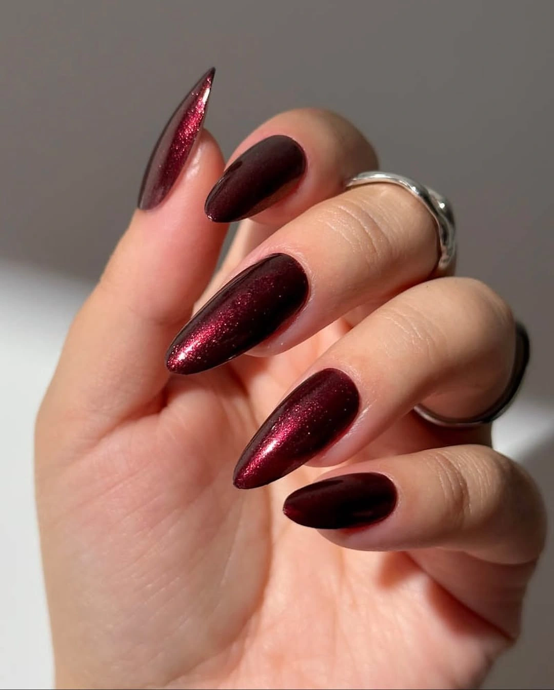 Deep burgundy almond nails with a rich reflective glossy finish