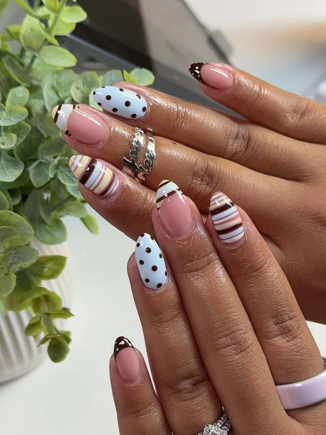 Pink almond nails with dots stripes and small brown floral details