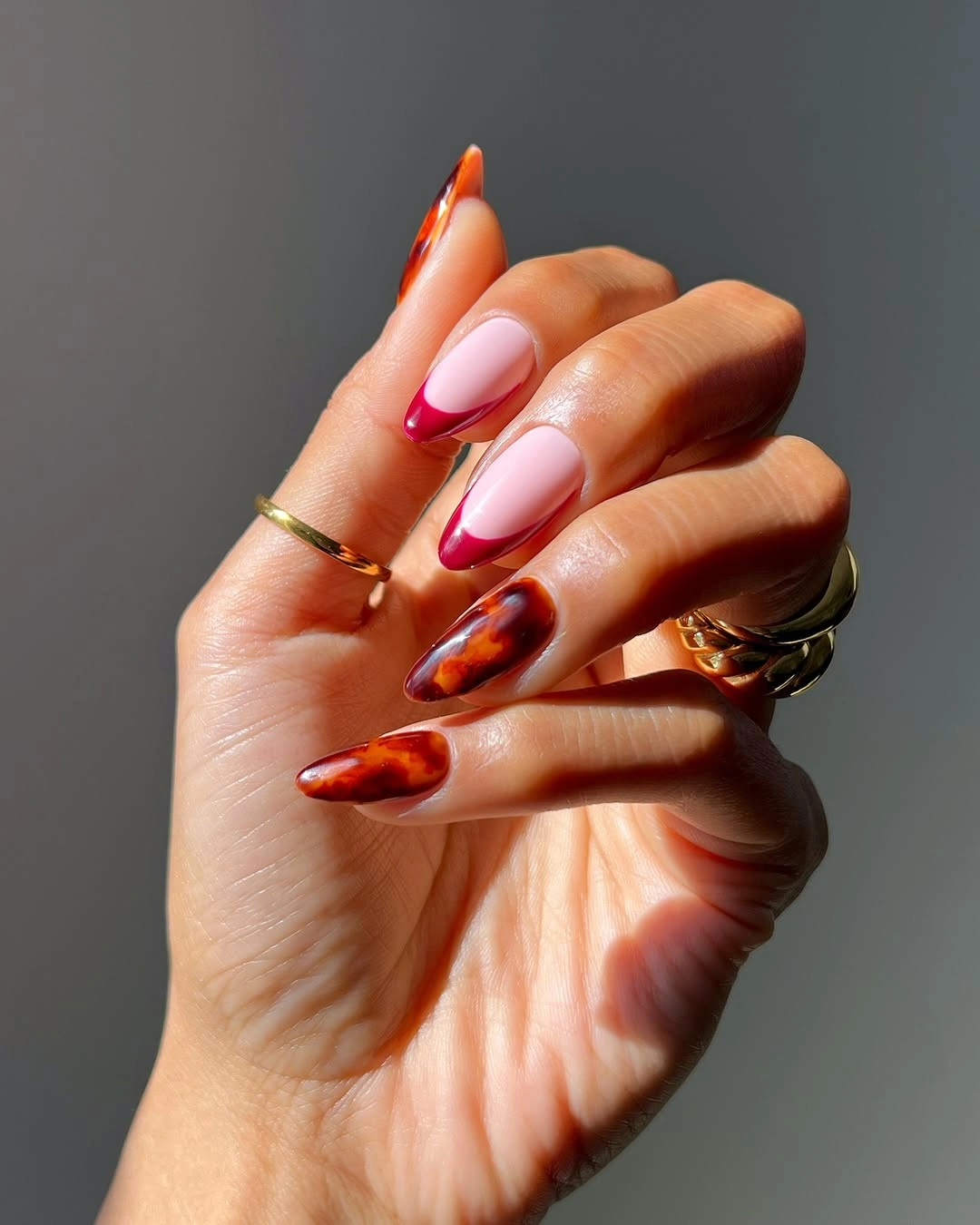 Orange pink and red almond nails with curved French sections