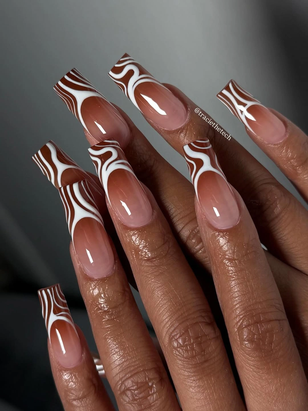Chocolate brown coffin nails with white wavy linework and nude bases