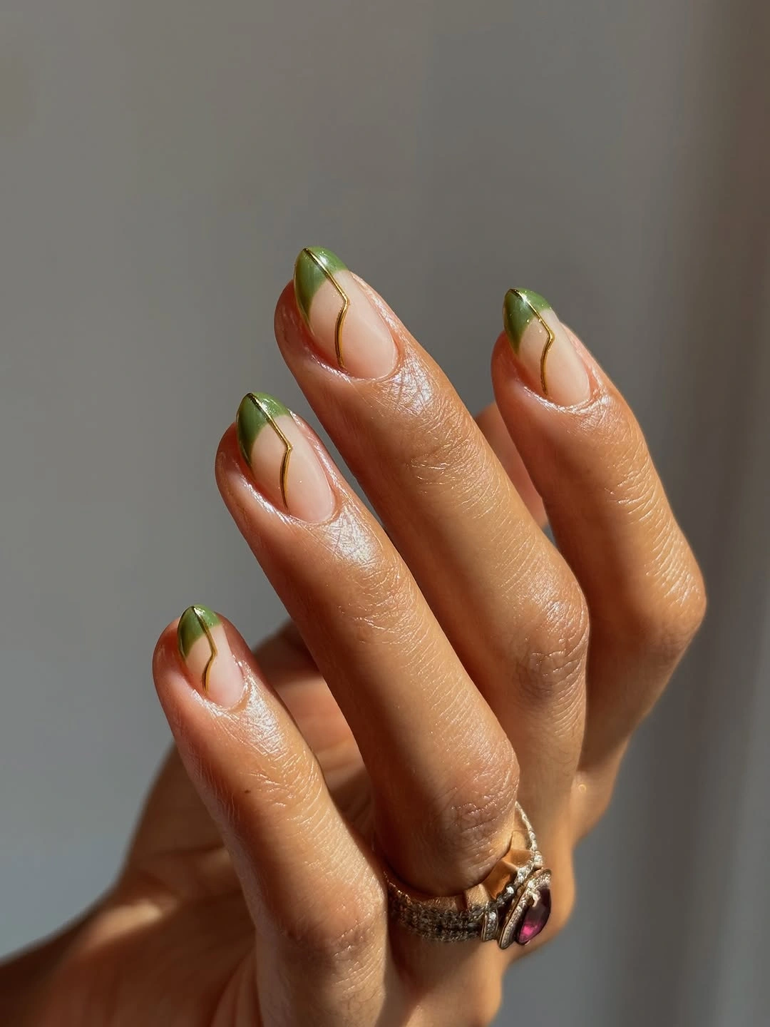 Short almond nails with sheer nude bases and olive green French tips