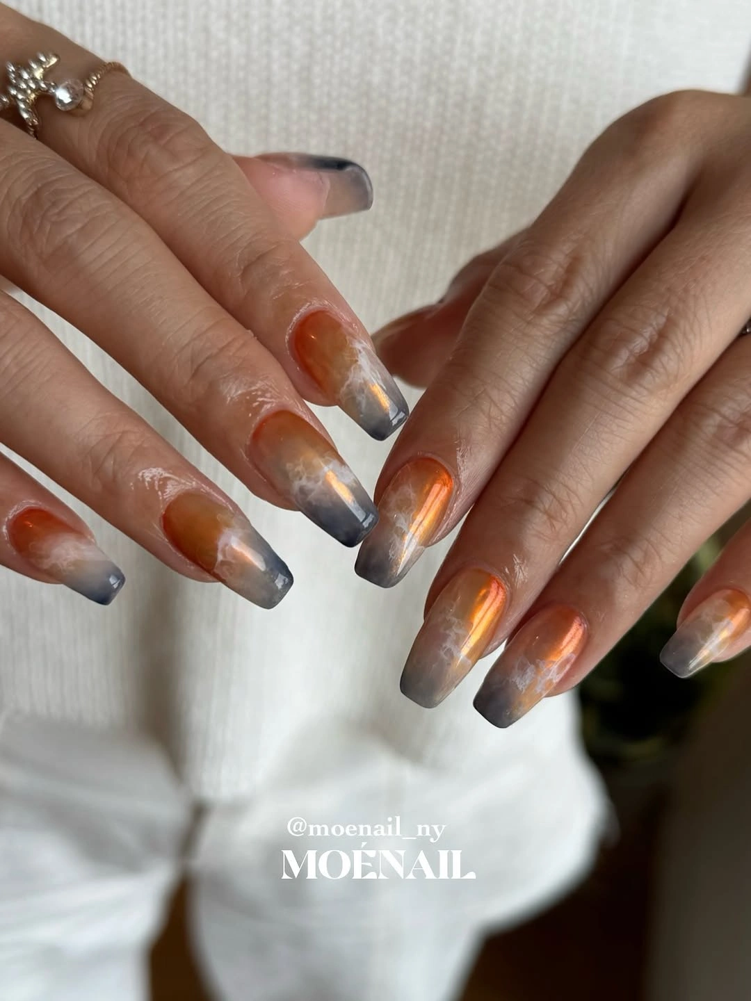 Long square nails with smoky cool tones and warm copper reflective accents