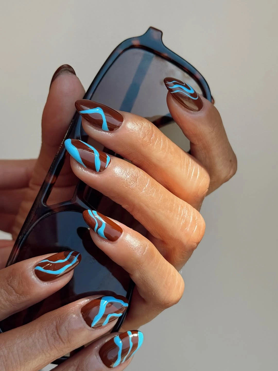 Long almond nude nails with bright turquoise curved line accents