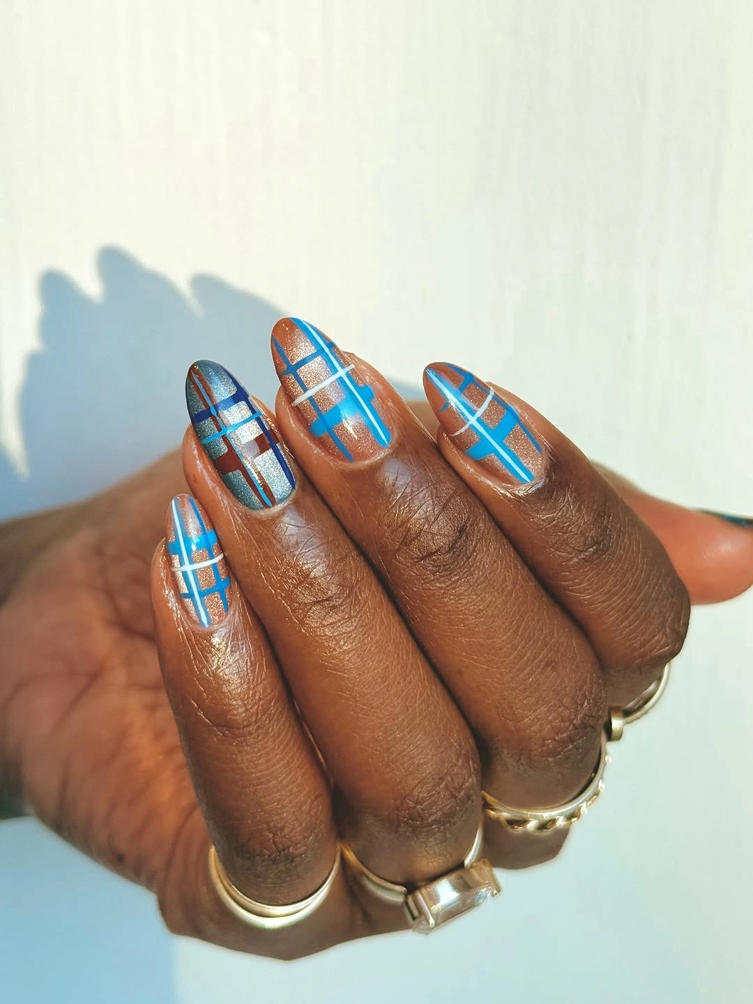 Medium almond neutral nails with bright blue plaid lines and open space
