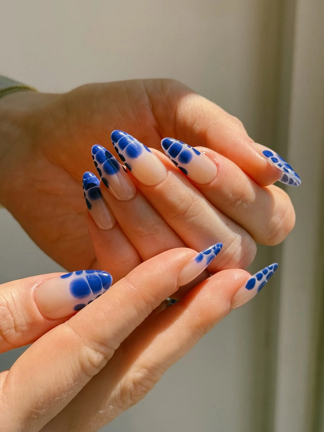 Almond nails with royal blue tips and clustered blue dot accents