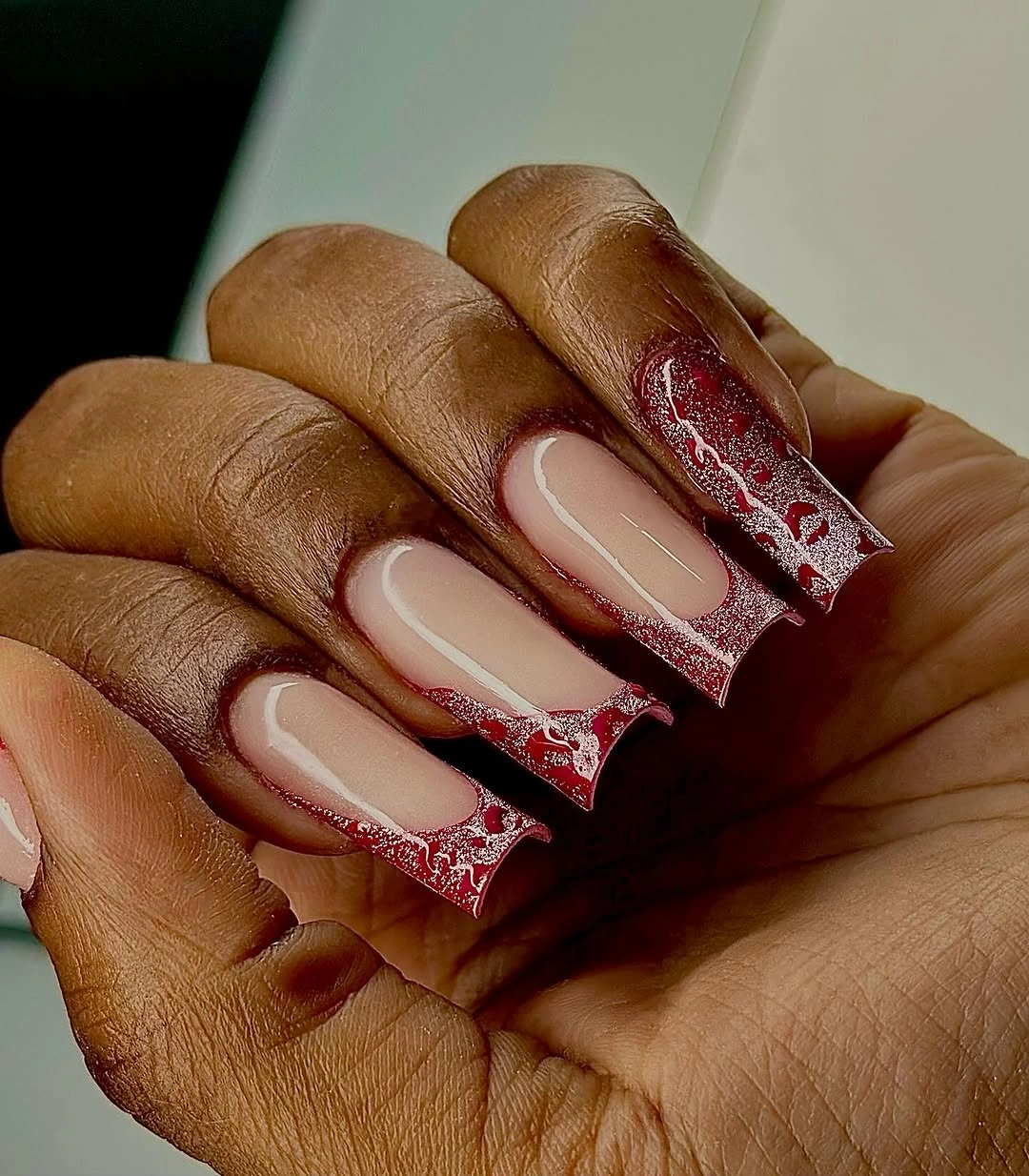 Medium coffin neutral nails with red glitter edges on dark skin