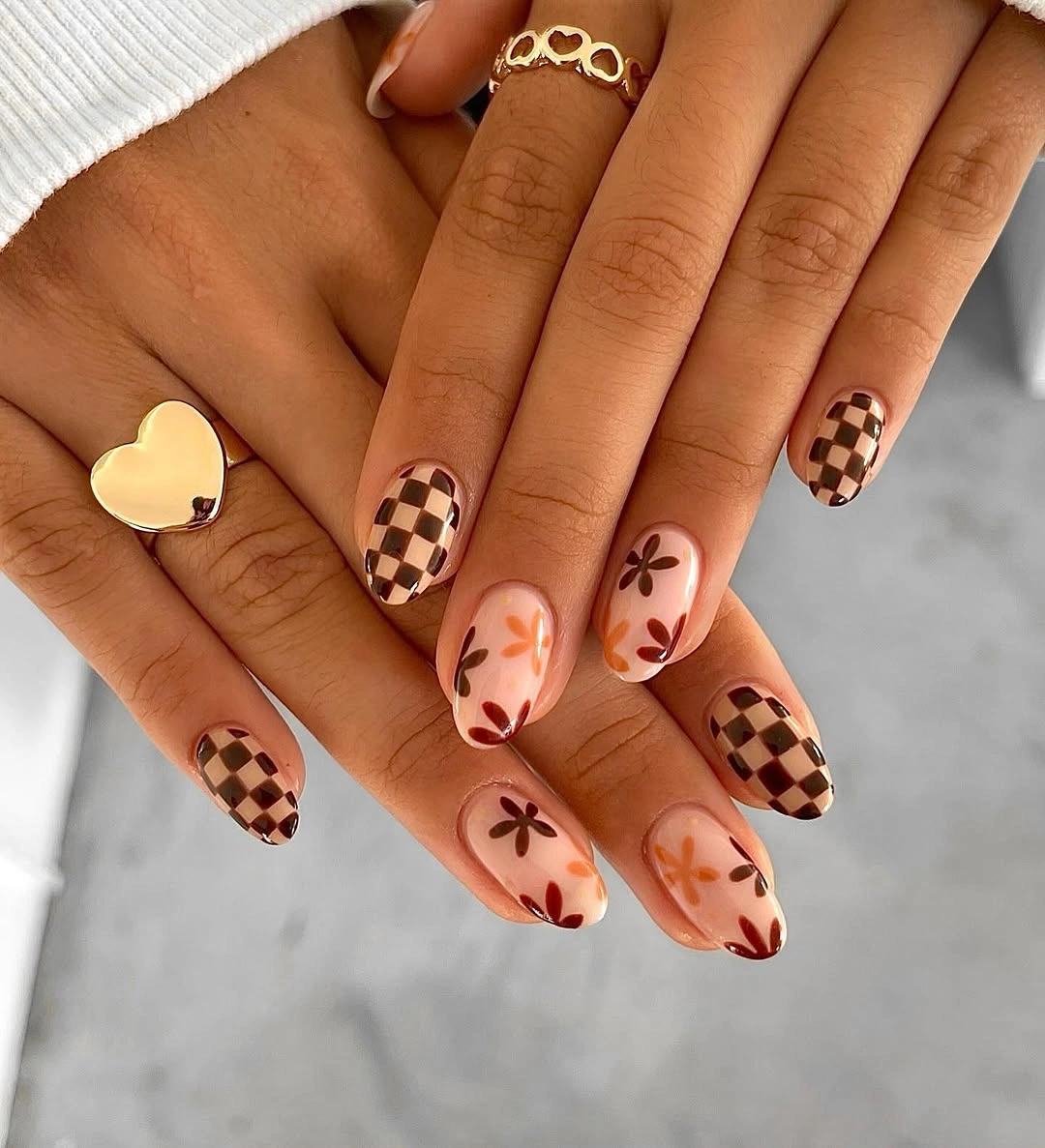 Nude almond nails with brown checkerboard tips and flowers