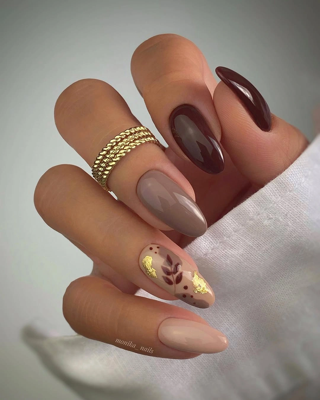 Long taupe almond nails with a small floral gold accent
