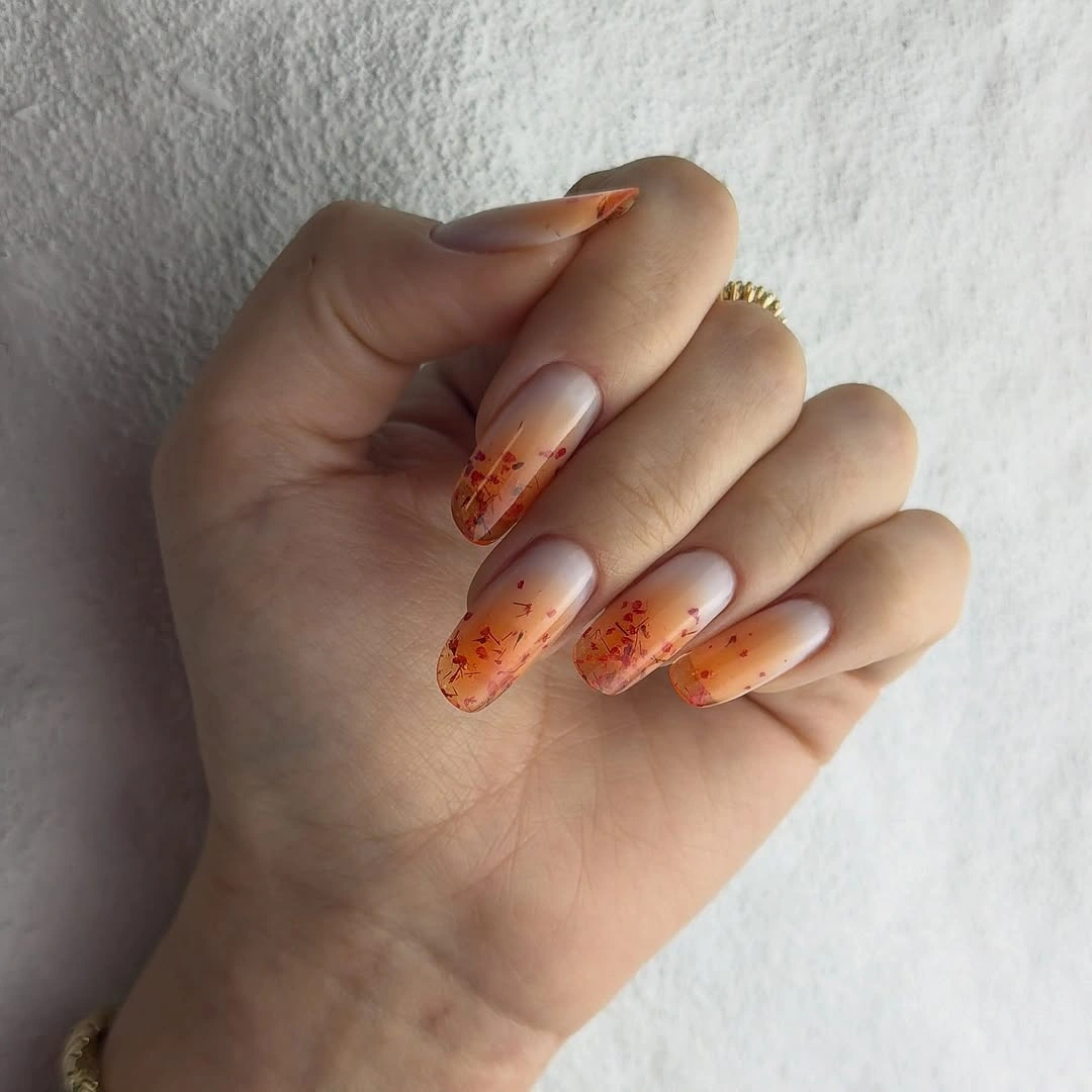 Long nude almond nails with orange brown dotted tips