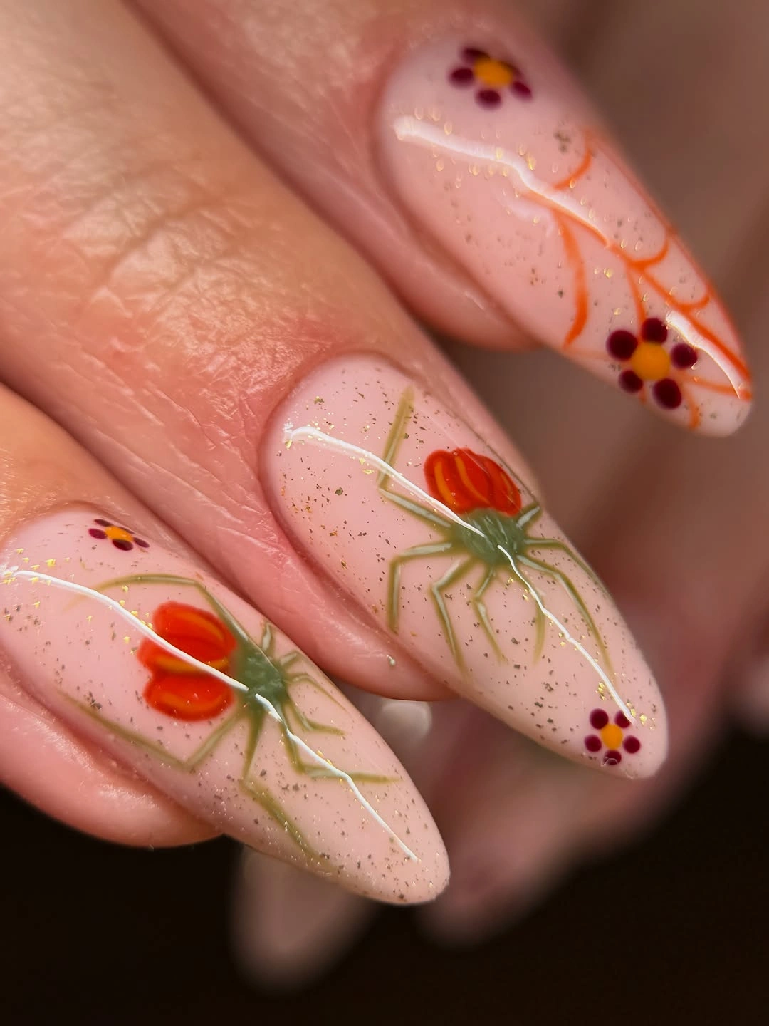 Nude almond nails with orange flowers green stems and dots