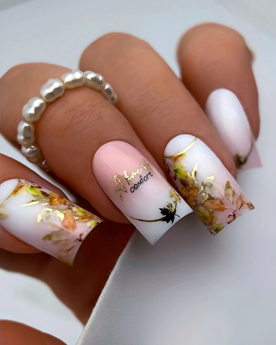 Milky white nails with botanical art and scattered gold foil