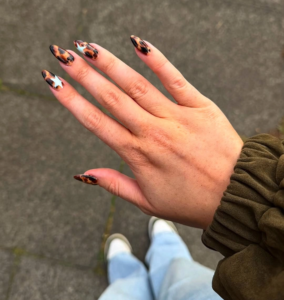 Medium almond nude nails with orange and black graphic tips