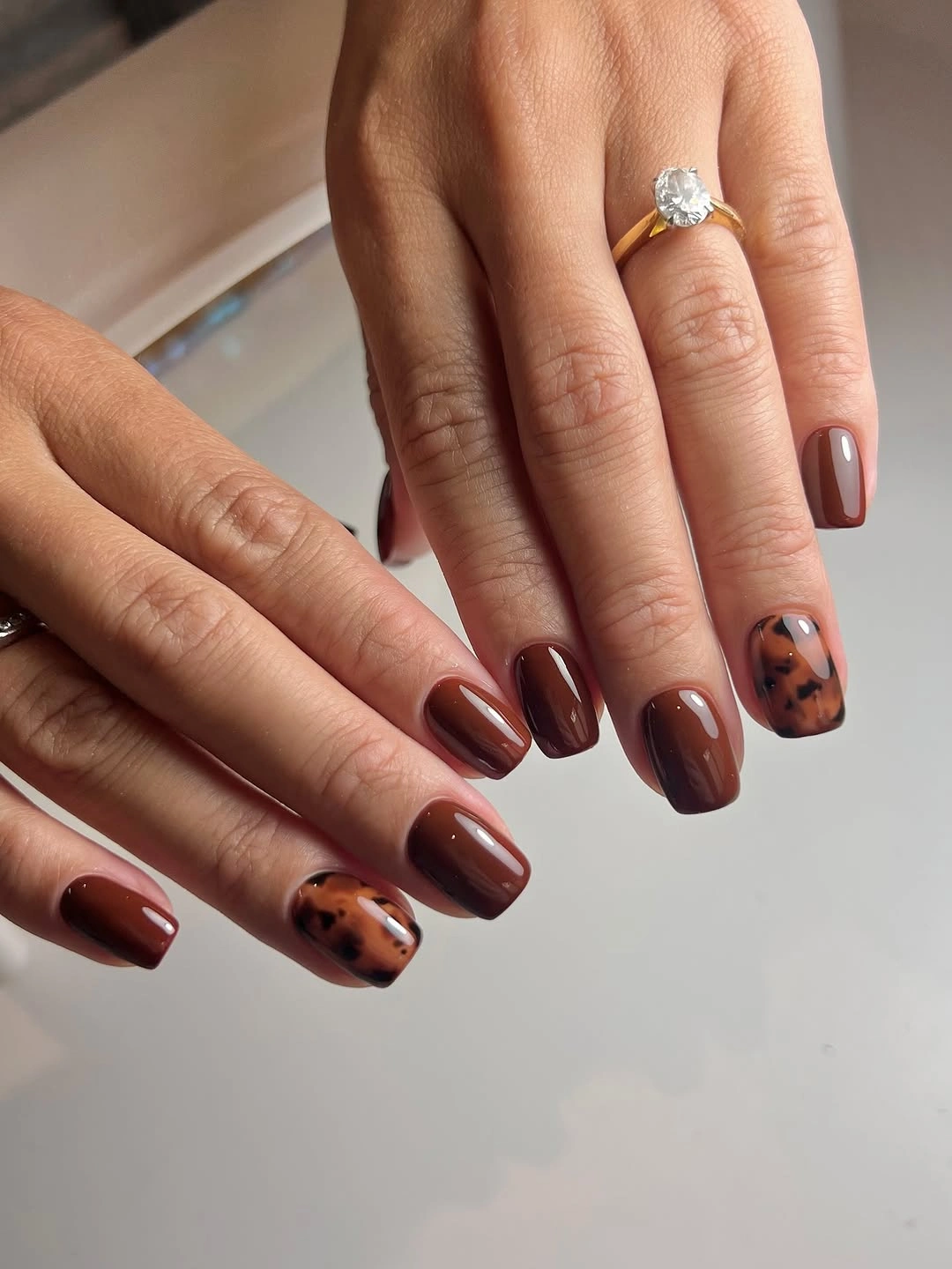 Medium glossy brown nails with one tortoise accent
