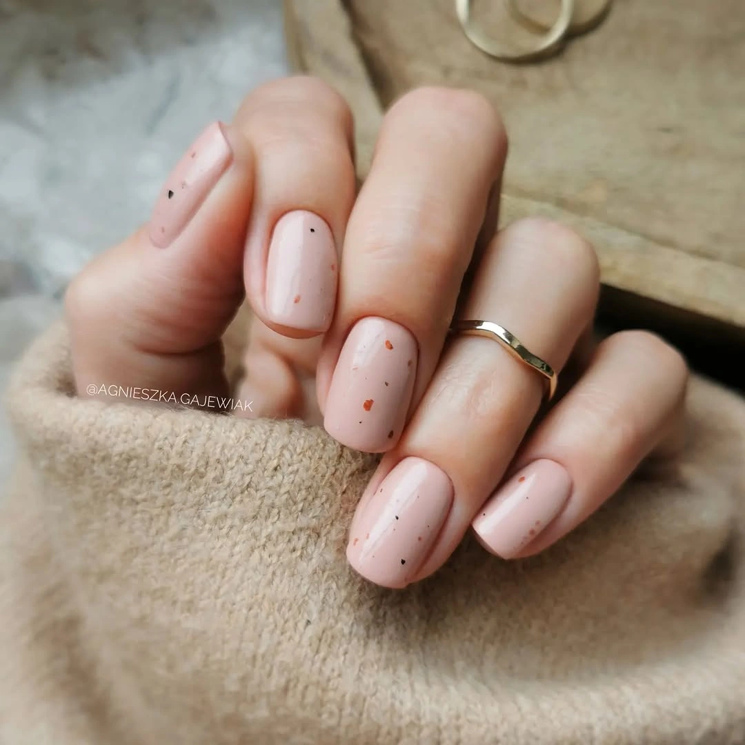 Short nude nails with tiny delicate dark speckles