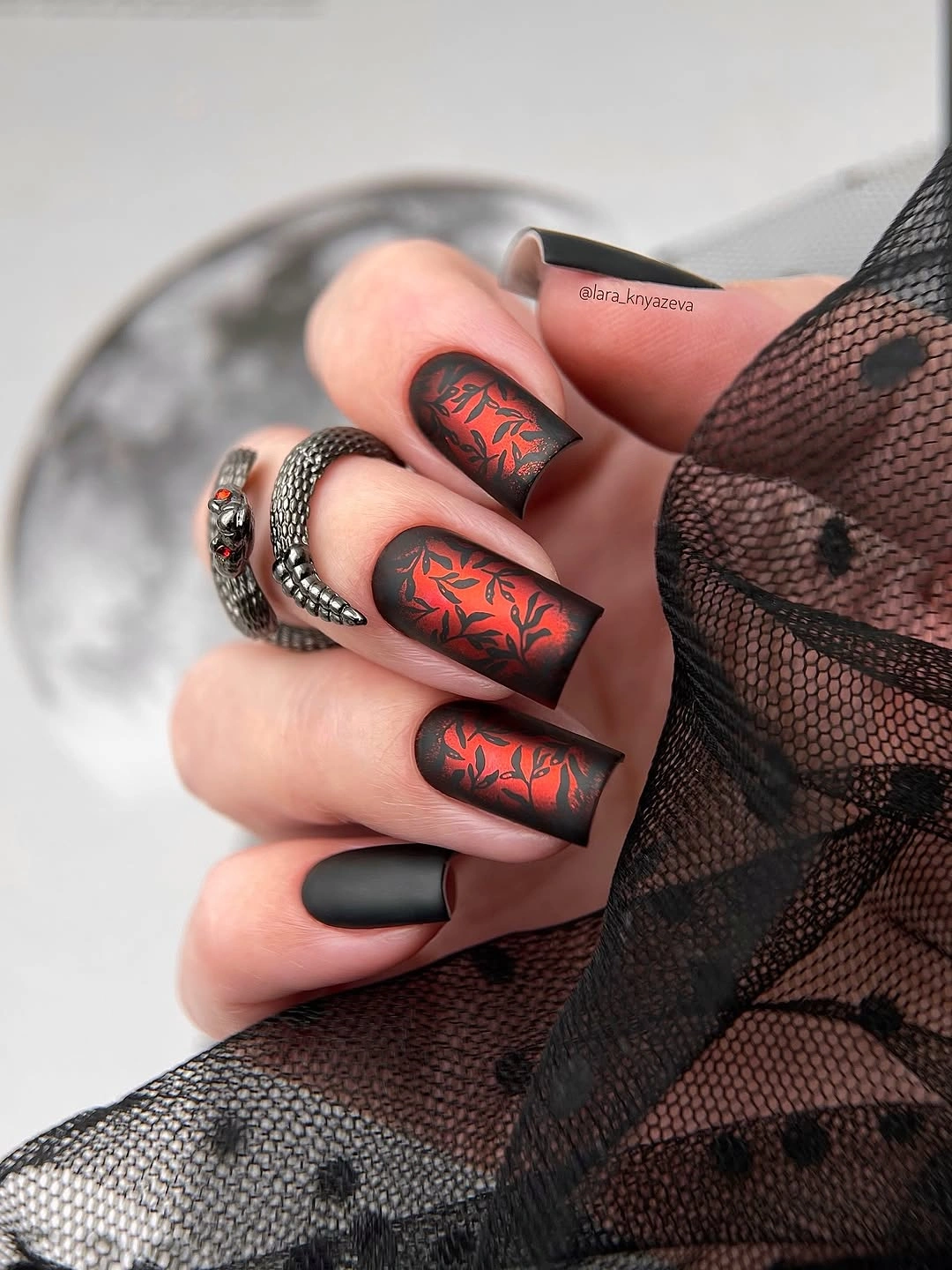 Short square black nails with red-orange abstract accent lines