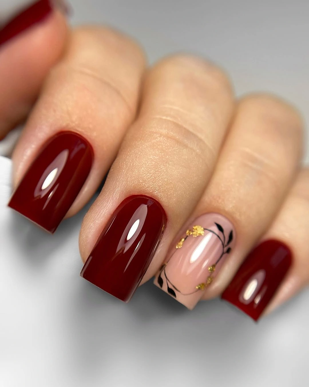 Glossy burgundy square nails with pale pink accent detail