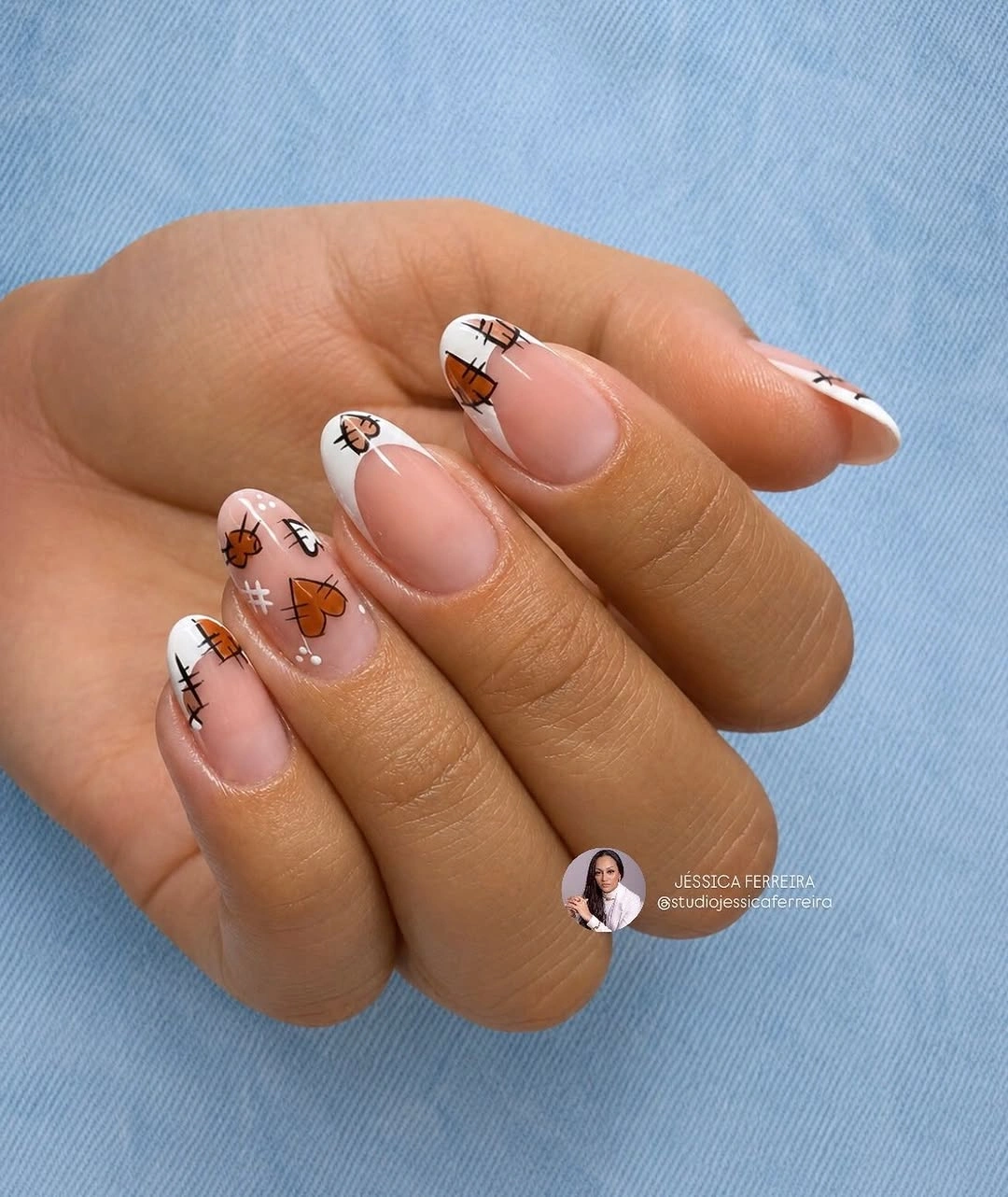 Nude oval nails with dark tips and warm patterned accents