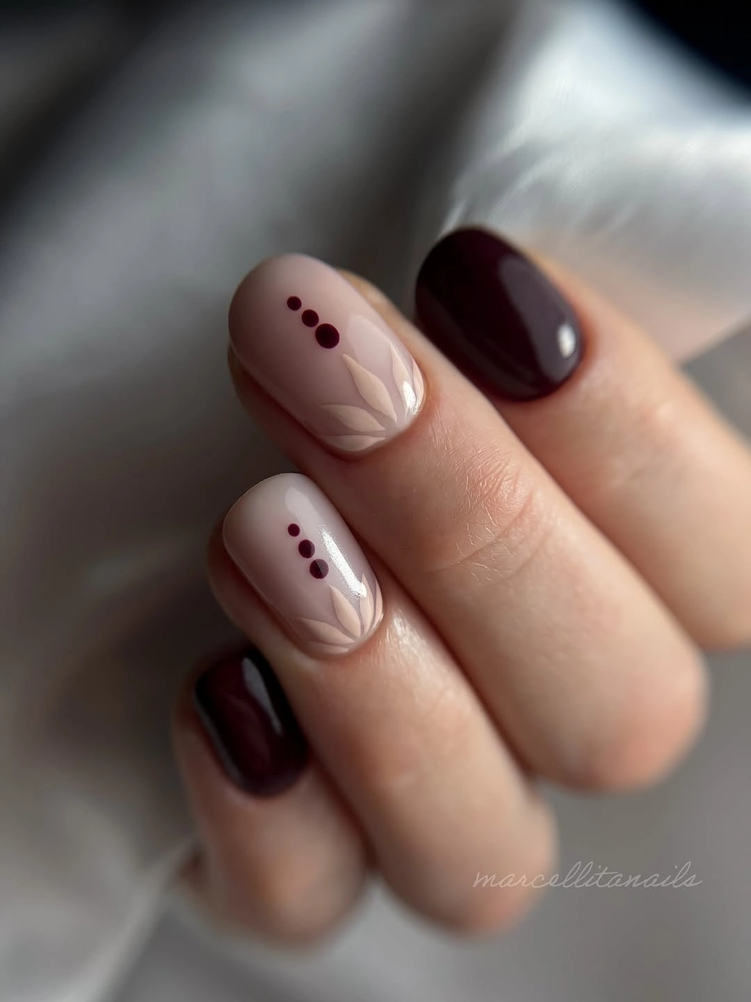 Burgundy nude almond nails with small burgundy dot accents