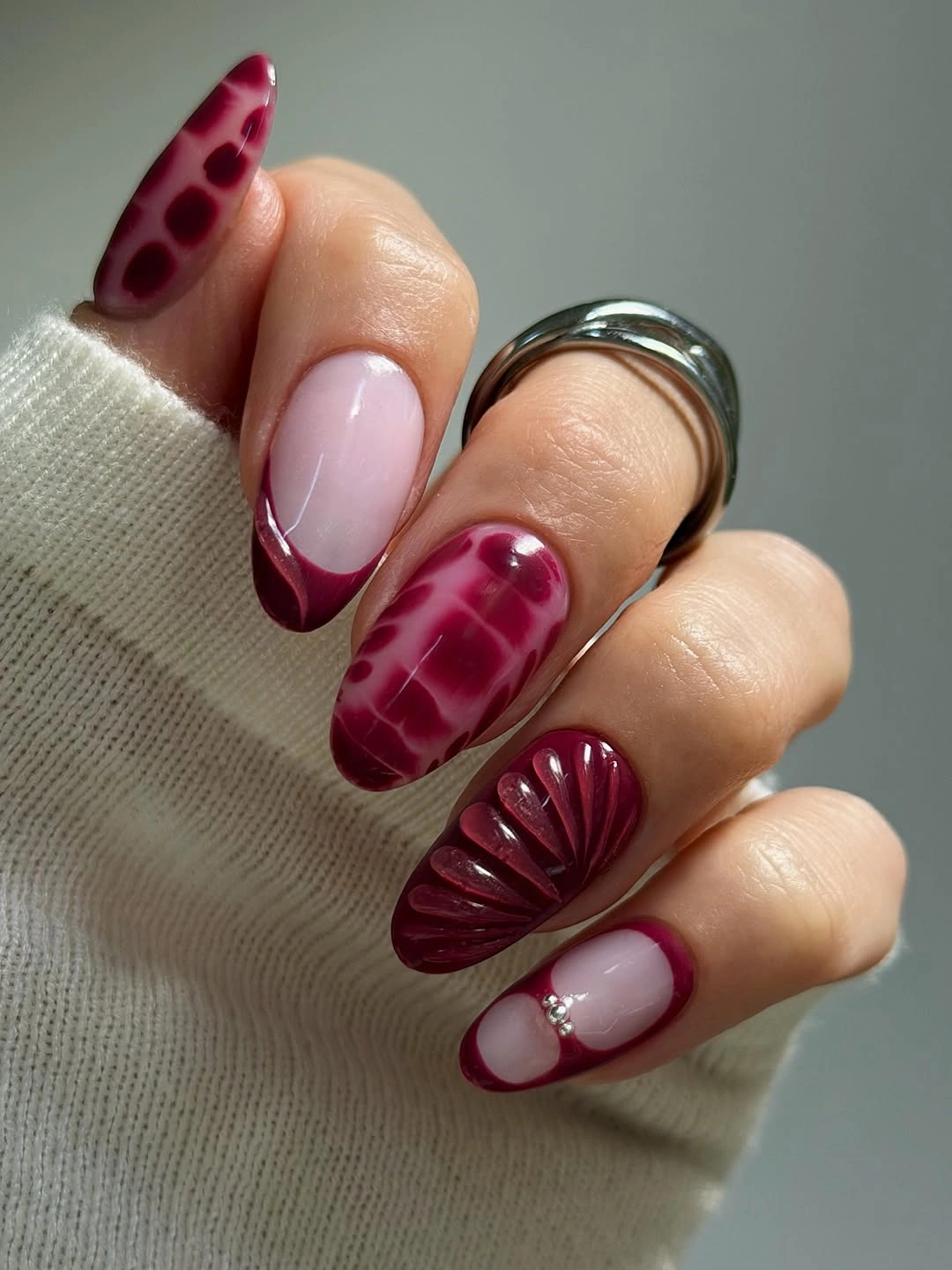 Burgundy fuchsia nude almond nails with curved textured patterns